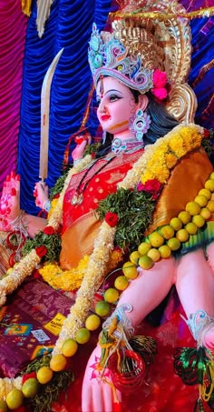 a statue of a woman sitting on top of a red cloth covered floor next to blue curtains