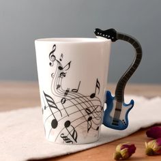 a coffee cup with musical notes on it sitting on a table next to some nuts