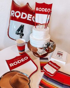 a table topped with plates and cups next to a red rodeo sign on the wall