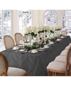 a dining room table is set with white flowers and place settings