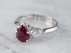 Always in style, rings such as this one can be worn as engagement rings, thanks to their high quality and the secure style of this setting. We've set the center of this one with a pretty, glowing red ruby cut into a romantic teardrop shape. The bright white diamonds reflect plenty of light into the deep, luscious red center stone. This ring will look well with a variety of bands, from a plain circle to a ruby and diamond eternity band. Metal: 18K White Gold Gem: Ruby 1.03 Carat Gem Measurements: Masonic Ring, Ring Ring, Ruby Engagement Ring, Silver Wedding Rings, Ruby Jewelry, Ruby Diamond, Eternity Band Diamond, Diamond Eternity, Three Stone Rings