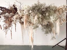 an arrangement of dried flowers hanging from a ceiling in front of a wall with white walls