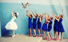 a group of women standing next to each other in front of a wall with a cat on their shoulders