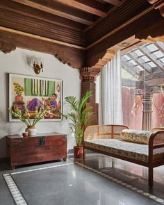 a living area with a couch, table and potted plant on the floor in front of a window