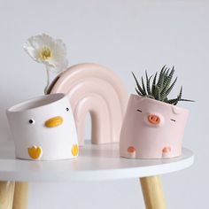 two small pots with plants in them sitting on a table