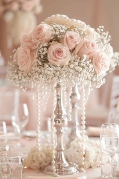 a tall vase filled with pink roses and baby's breath flowers on top of a table