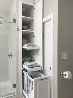 a bathroom with white cabinets and shelves filled with towels