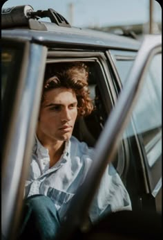 a man sitting in the driver's seat of a car with his head out the window