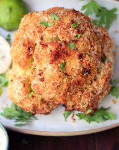 crab cakes on a plate with parsley garnish and limes in the background