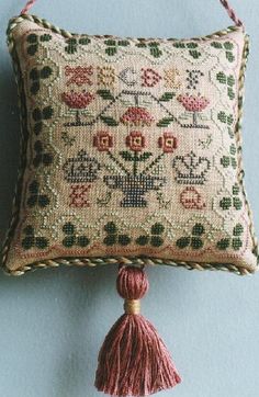 a decorative pillow with a tassel hanging from it's side on a blue wall