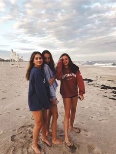 three girls are standing on the beach together