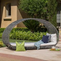 an outdoor daybed with cushions and pillows on the ground in front of a house