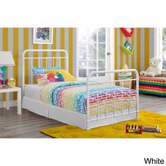 a white metal bed frame in a bedroom with yellow striped walls and rugs on the floor