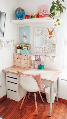 a white desk and chair in a room with wood flooring, bookshelves and pictures on the wall