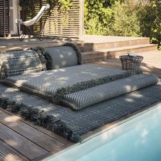 a couch and pillows on the ground next to a swimming pool