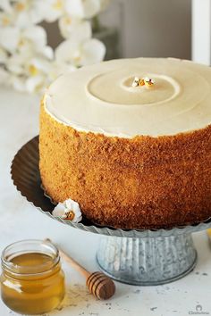 a cake sitting on top of a metal platter next to a jar of honey