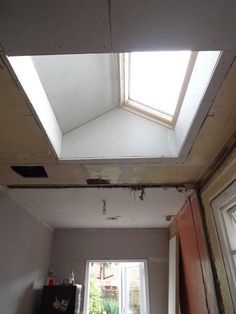 an unfinished room with a skylight in the ceiling and a window on the far wall