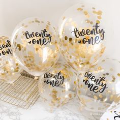 gold confetti balloons with the words twenty one printed on them are sitting on a table