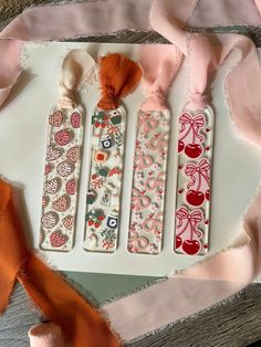 three decorative bookmarks with bows and ribbons around them on a piece of paper that has been cut out