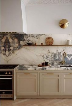 a kitchen with marble counter tops and gold faucets on the wall above it