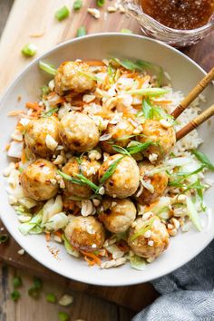 a white bowl filled with meatballs and rice on top of a wooden cutting board