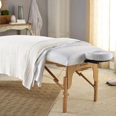 a wooden massage table with a white cover on it's back and foot rest