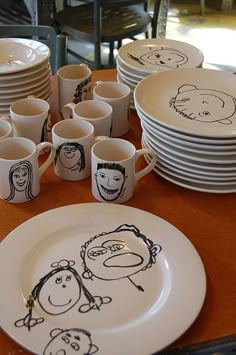 a table topped with lots of white plates covered in cartoon drawn cups and saucers