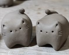 two clay cats sitting next to each other on a table