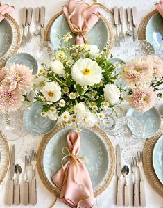 the table is set with plates, silverware and pink napkins for an elegant look