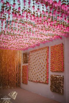 pink and gold decorations hanging from the ceiling in a room with two paintings on the wall