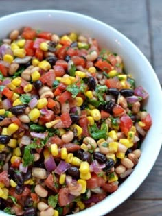 a white bowl filled with black eyed peas, corn and cilantro salsa on top of a wooden table