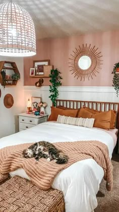 a cat laying on top of a bed in a room with pink walls and wooden furniture