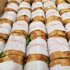 many rolls wrapped in paper with red string on them are stacked up and ready to be eaten