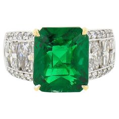 This absolutely breathtaking tsavorite and diamond ring was crafted in solid 18k white gold with a solid 18k yellow gold center basket that carries a gorgeous, emerald cut, natural tsavorite stone. The large solitaire is perfectly prong set and GIA certified as weighing exactly 8.71 carats in weight, displaying a super attractive and rich green color that brings such a desirable look to this piece. Its rare to find a tsavorite of this large size! The solitaire is further accented with approximat Luxury Emerald Cut Tsavorite Diamond Ring, Luxury Tsavorite Emerald Ring, Luxury Exquisite Multi-stone Emerald Ring, Luxury Tsavorite Multi-stone Emerald Ring, Gold Basket, Classic Engagement Ring Solitaire, Gold Cocktail Ring, Gold Cocktail