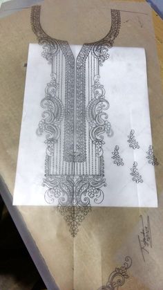 a piece of paper that is on top of some kind of cloth with an intricate design