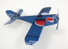 an origami model airplane with pepsi logo on the side and wings, sitting on a white surface