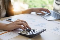 a person typing on a calculator at a desk