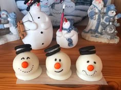 three snowmen with hats on their heads are sitting in front of other christmas figurines