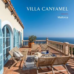 an outdoor patio with wicker furniture and blue shutters overlooking the ocean in mallorca, mexico