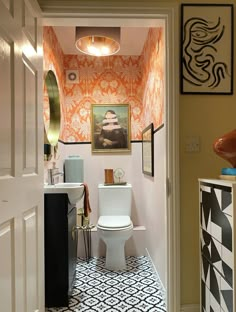 a white toilet sitting inside of a bathroom next to a sink under a light fixture