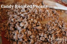 candy roasted pecans on a cutting board next to a wooden spatula with the words candy roasted pecans