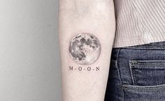 a woman's arm with a small moon tattoo on it