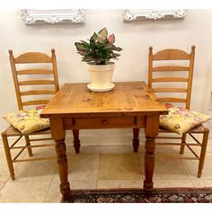 a wooden table with two chairs and a potted plant on top of the table