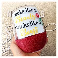 someone is holding up a wine glass with glitter on it that says, looks like a beauty drinks like a beast