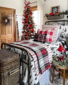 a bedroom decorated for christmas with red and black decorations on the bed, plaid comforter, and pillows