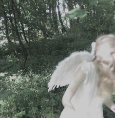 an angel is walking through the woods with her hair blowing in the wind and eyes closed