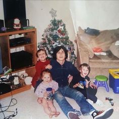 a family sitting in front of a christmas tree