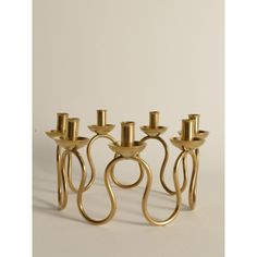 four brass candlesticks sitting next to each other on a white surface with one candle in the middle