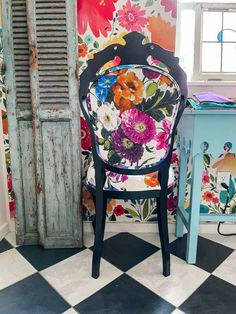 a chair sitting in front of a wall with flowers on it