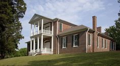 a large brick house sitting on top of a lush green hillside